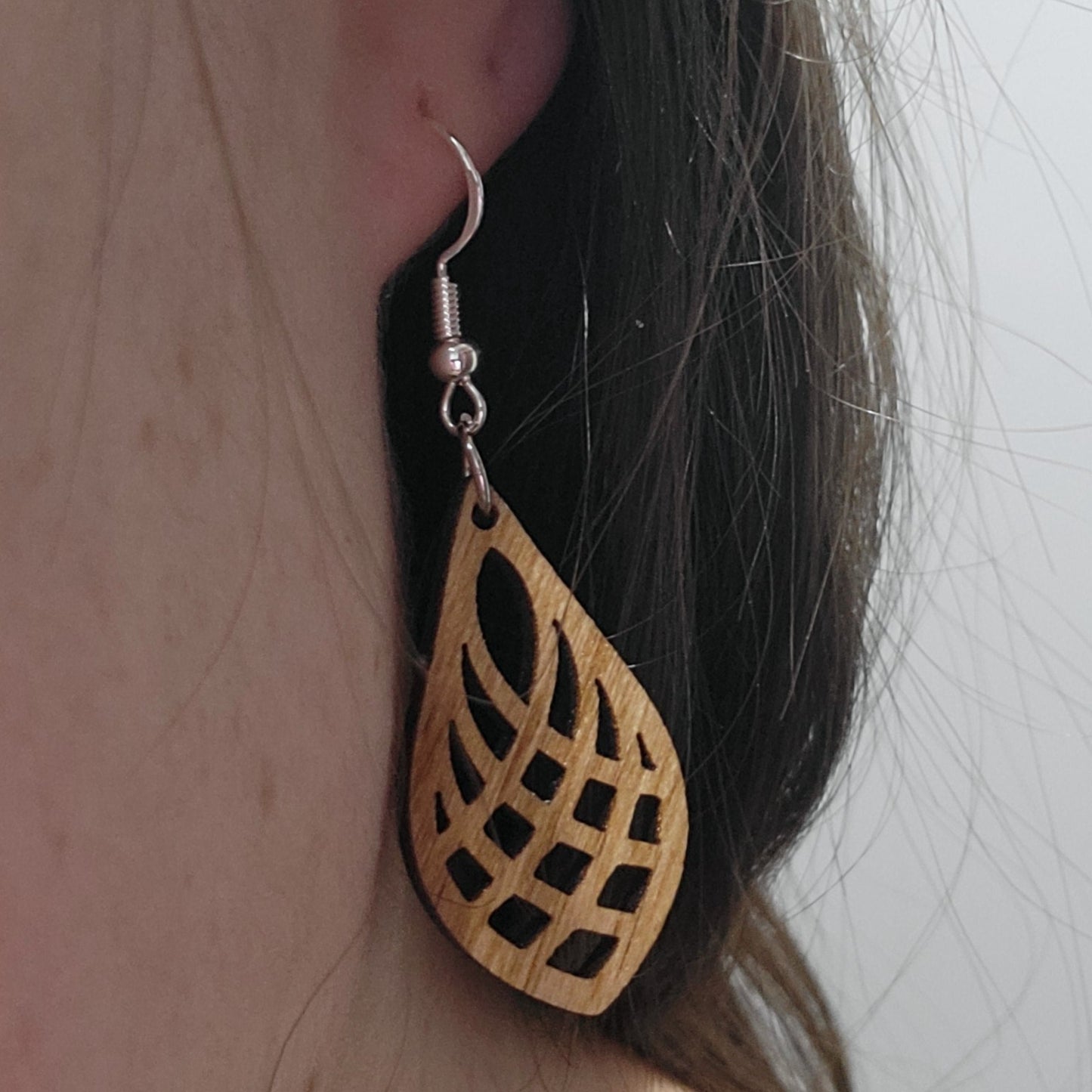 golden oak wooden laser cut teardrop patterned earring on ear