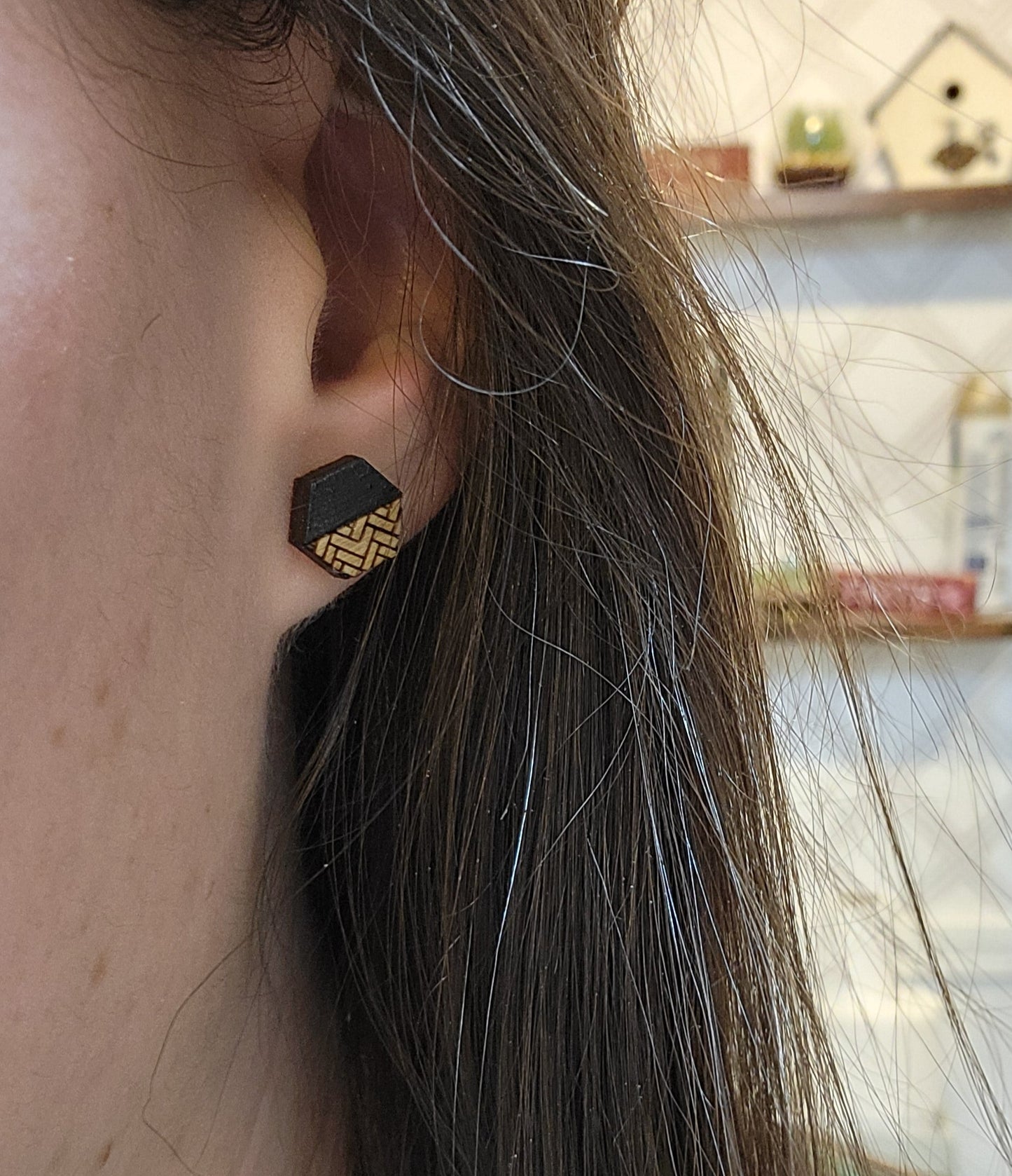 black and golden oak herringbone patterned hexagon-shaped wood engraved stud earrings on ears