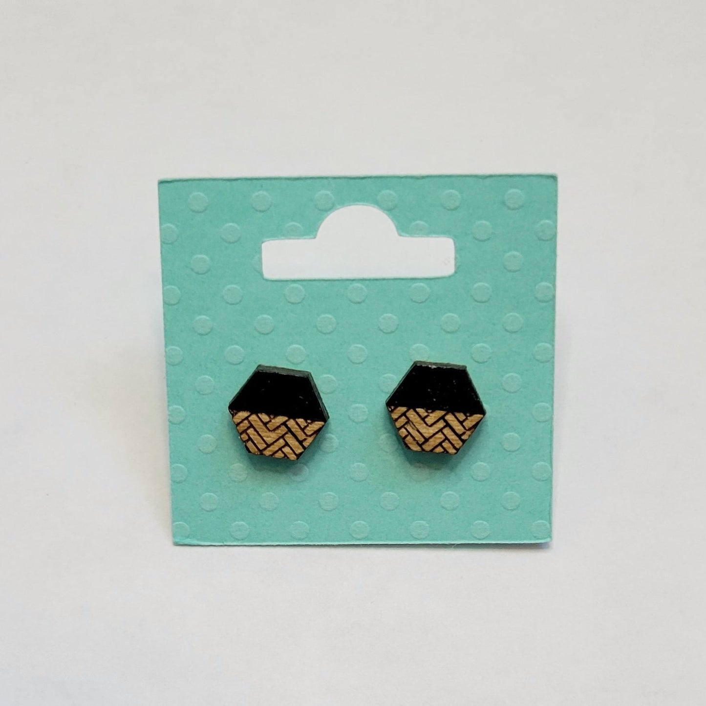black and golden oak herringbone patterned hexagon-shaped wood engraved stud earrings on a white background