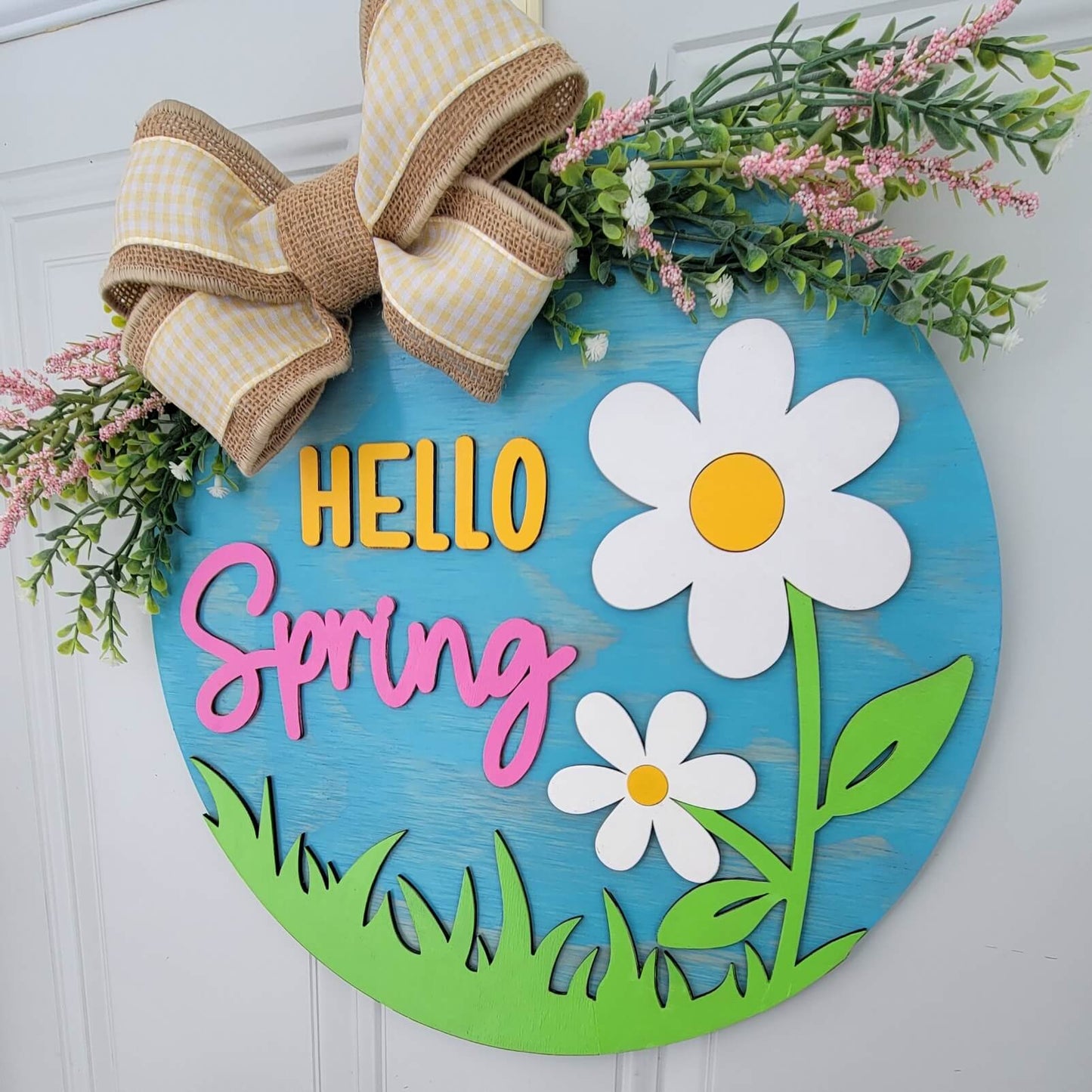 hello spring door hanger with white and yellow flowers with bow and spring greenery angled view hanging on door