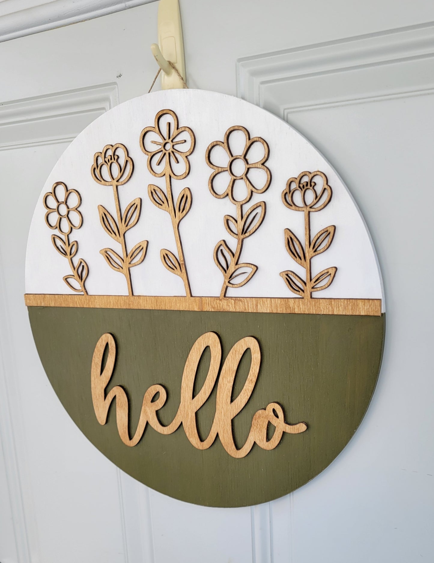 olive green, white and golden oak hello door hanger with cutout stemmed flowers hanging on door angled view