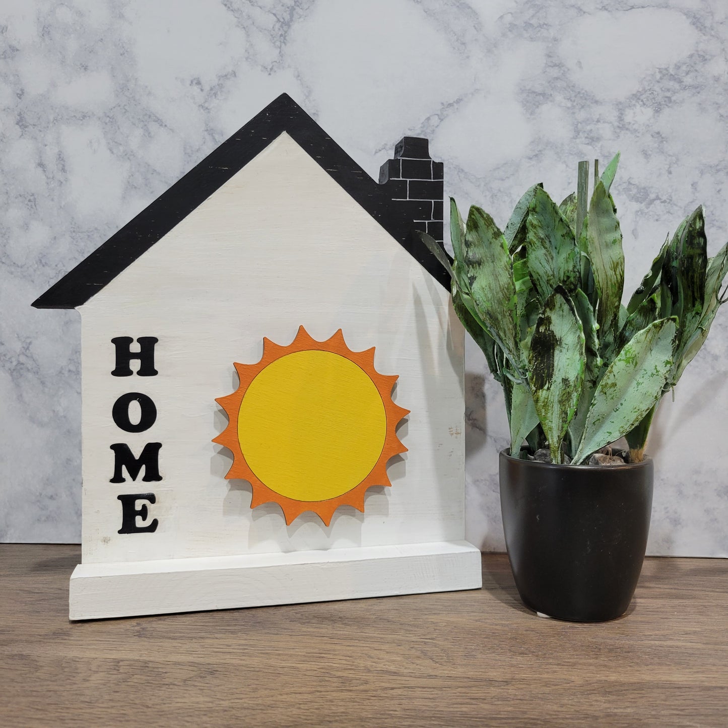 white and black house shaped wood interchangeable sign with the word home and a sun