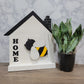 white and black house shaped wood interchangeable sign with the word home and bee