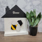 white and black house shaped wood interchangeable sign with the word home and bee