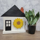 white house shaped sign with front door and sunflower