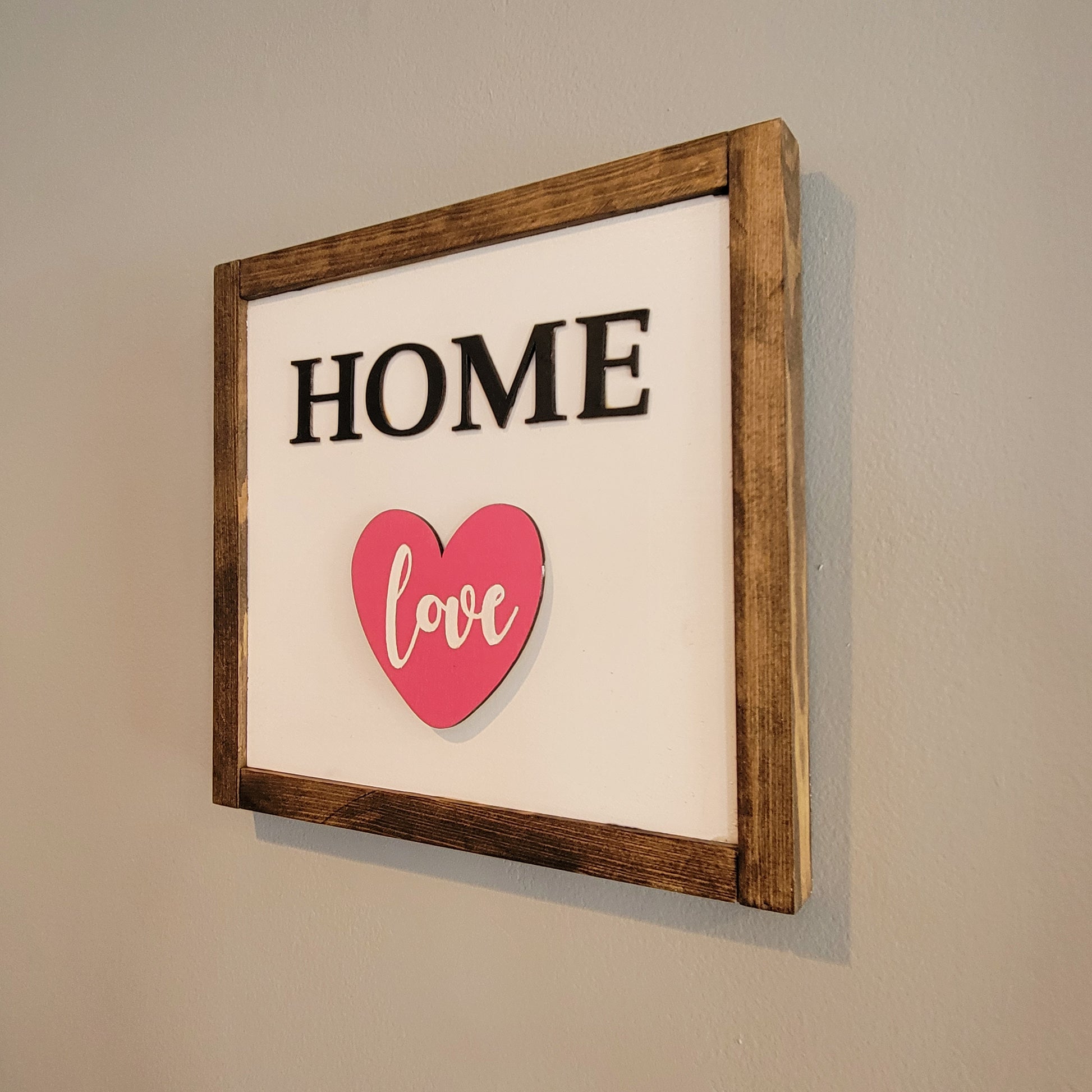 Dark wood framed home sign hanging on wall with love heart angle