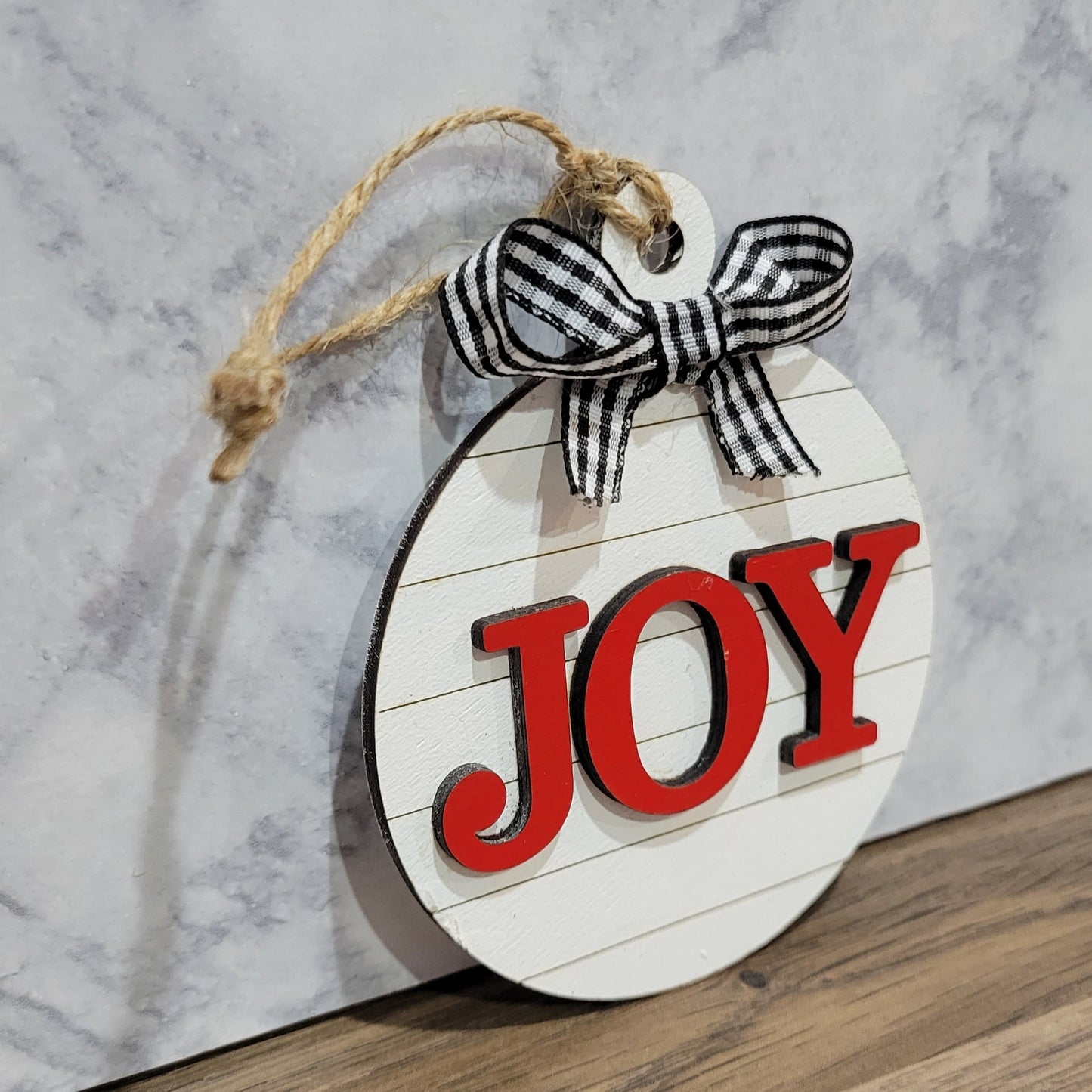 round white shiplap look striped christmas ornament with the word joy