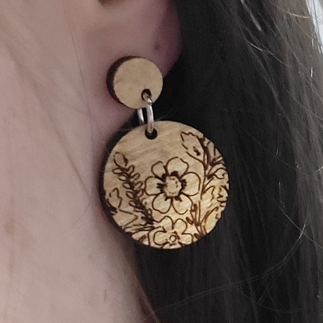 floral engraved wood earrings hanging on ears