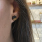 black and golden oak herringbone patterned hexagon-shaped wood engraved stud earrings on ears
