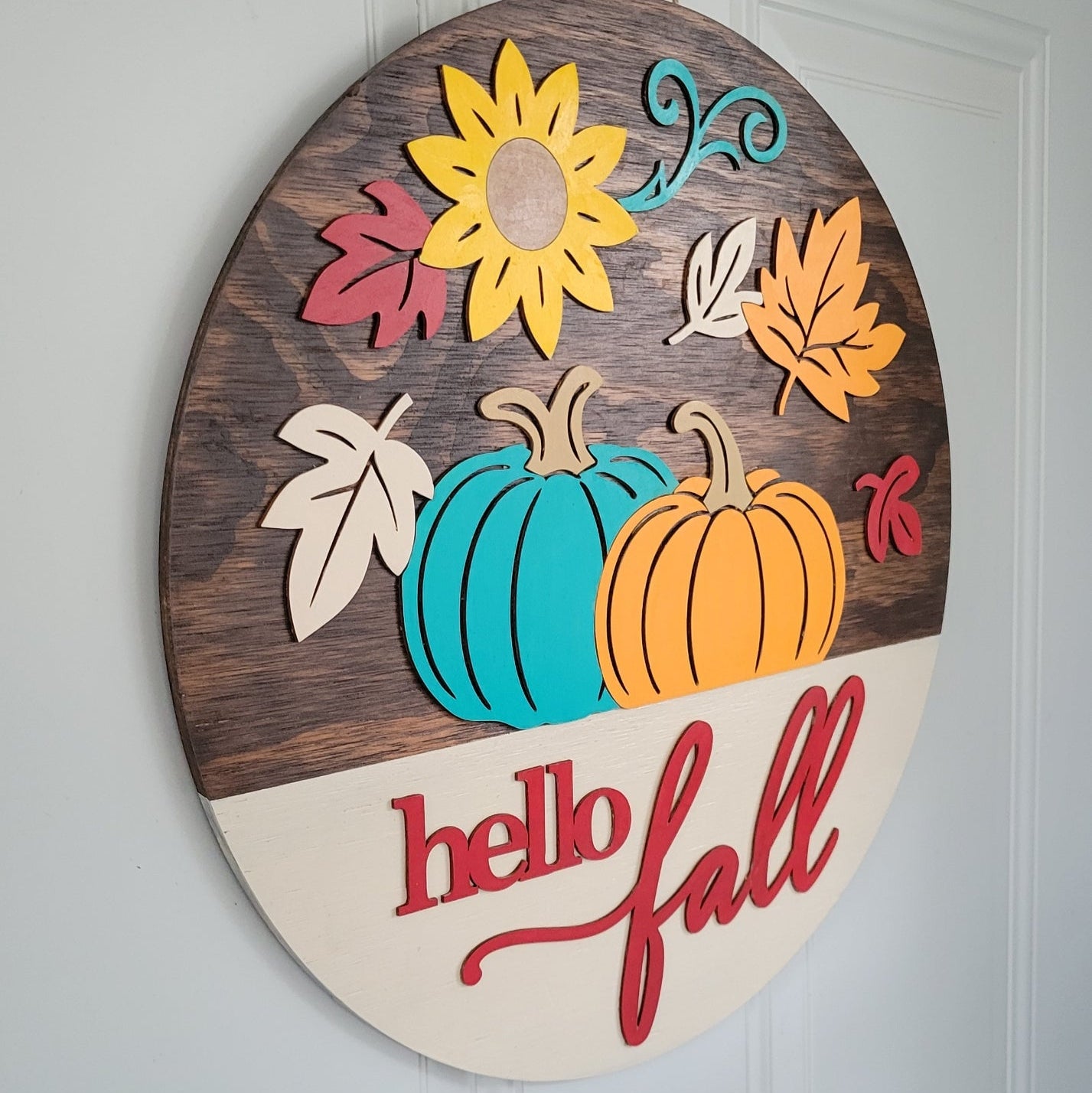 Hello Fall Door Hanger Kona Stain and Colorful Autumn Pumpkins and Leaves hanging on a door angle side view